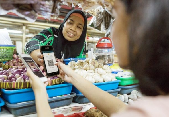 Pemilik UMKM melayani pelanggan dengan teknologi digital untuk transaksi modern