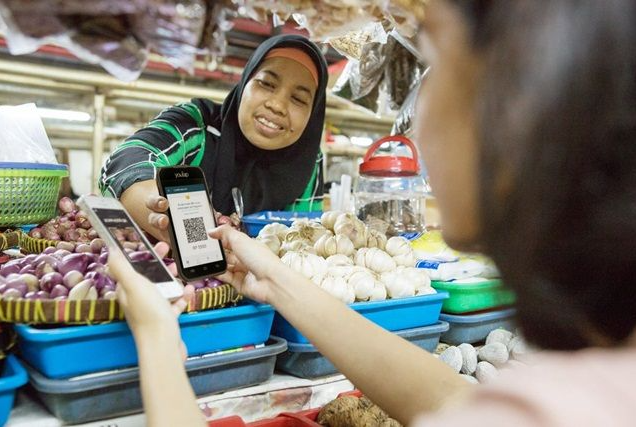 Pemilik UMKM melayani pelanggan dengan teknologi digital untuk transaksi modern